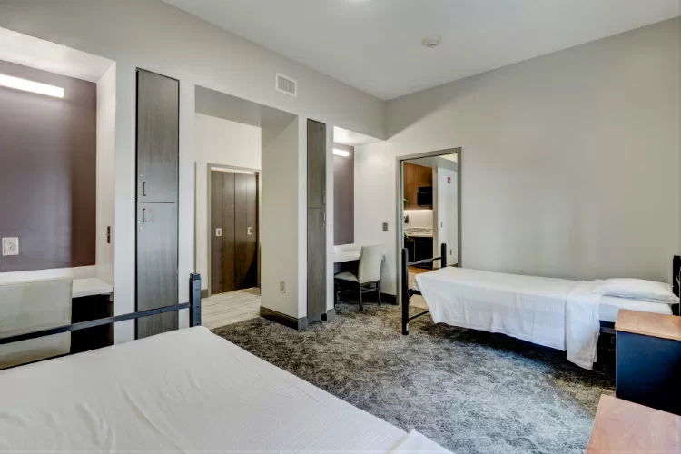 Spacious room with two beds, carpeted floor, and desk