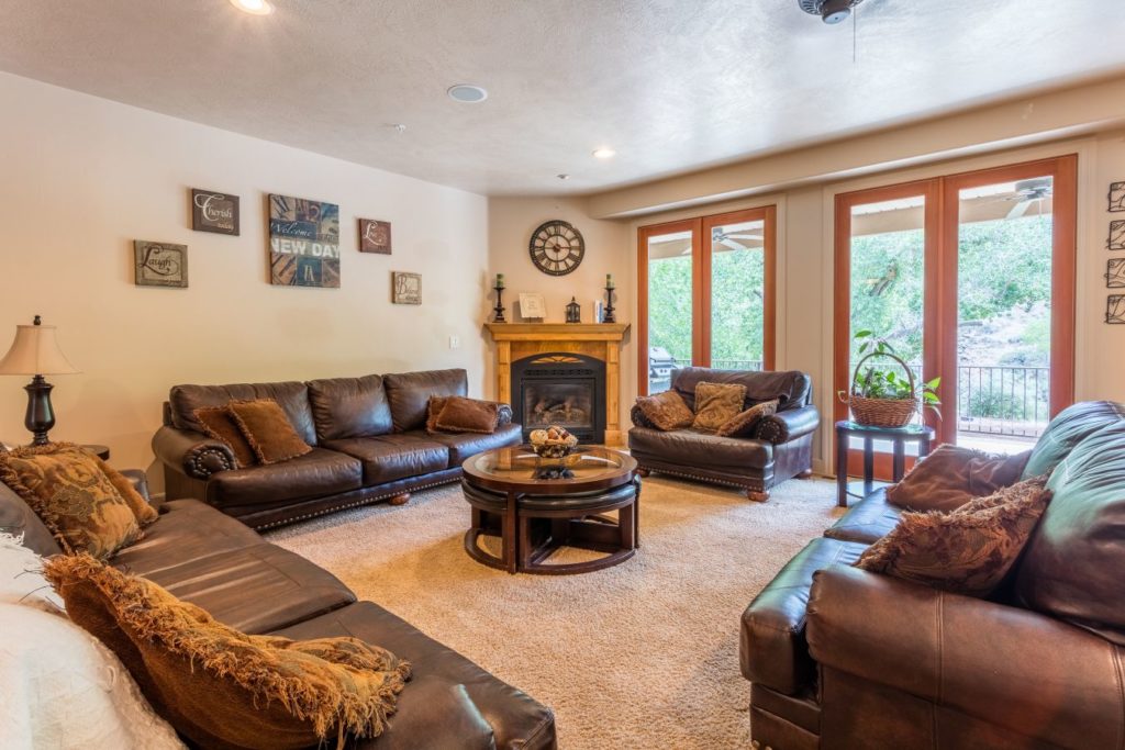 Living room with leather sofas, fireplace, and large windows.