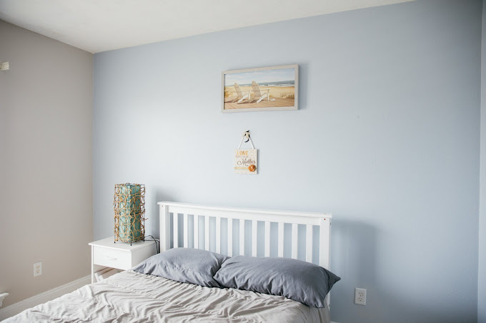 Single bed with white headboard and ocean artwork