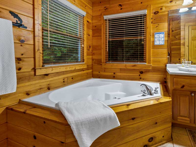 Bathroom with corner jacuzzi tub and wood-paneled walls