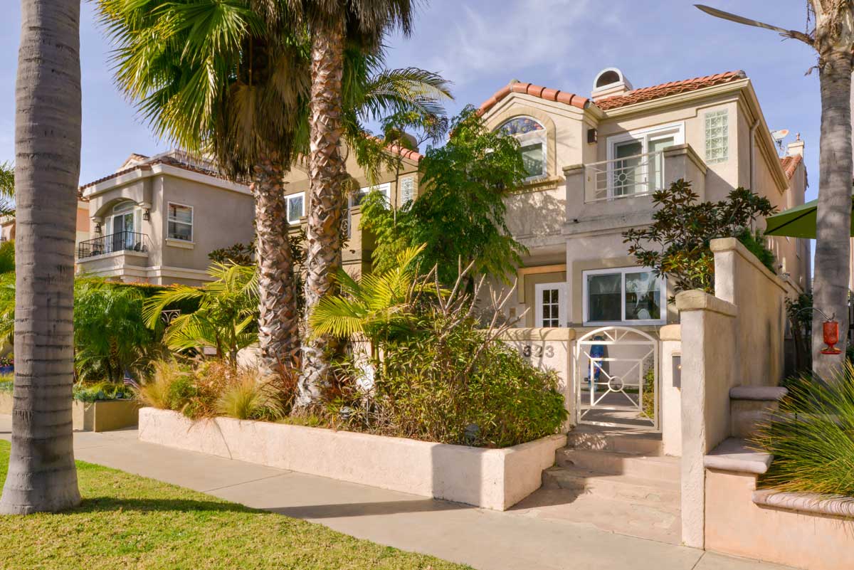 Exterior of building with palm trees and greenery.