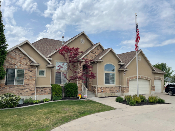 Tan house with U.S. flag and a red maple tree