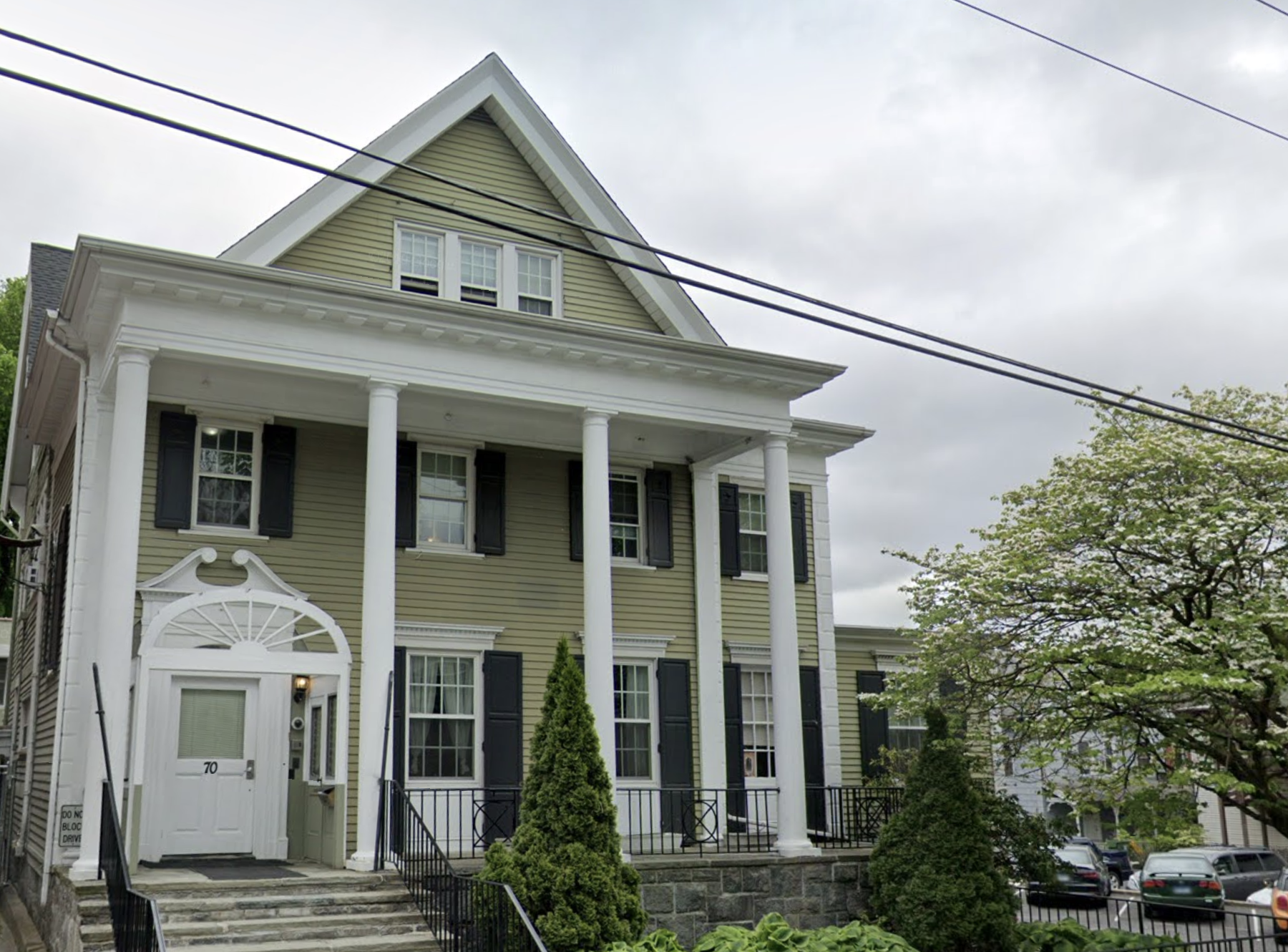 Two-story green building with white columns and front steps