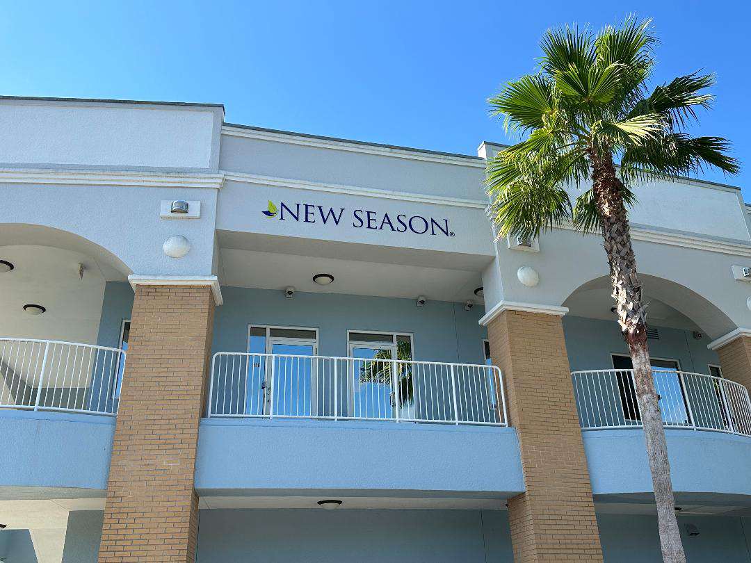 Palm tree and New Season rehab building under blue sky