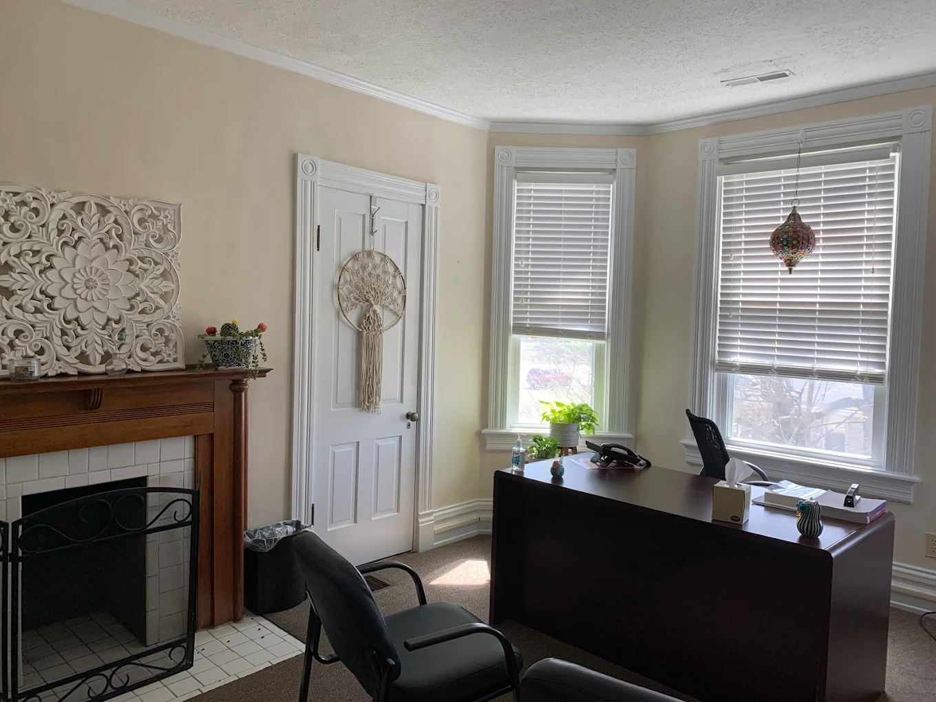 Private office with desk, chairs, fireplace, and windows