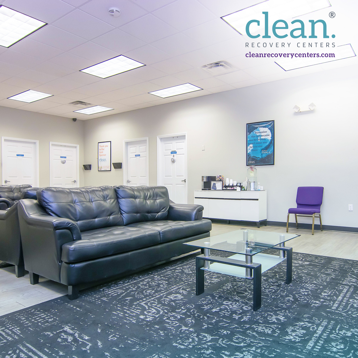 Modern waiting area with black leather sofas, glass coffee table, and refreshment counter at Clean Recovery Centers in Tampa, Florida