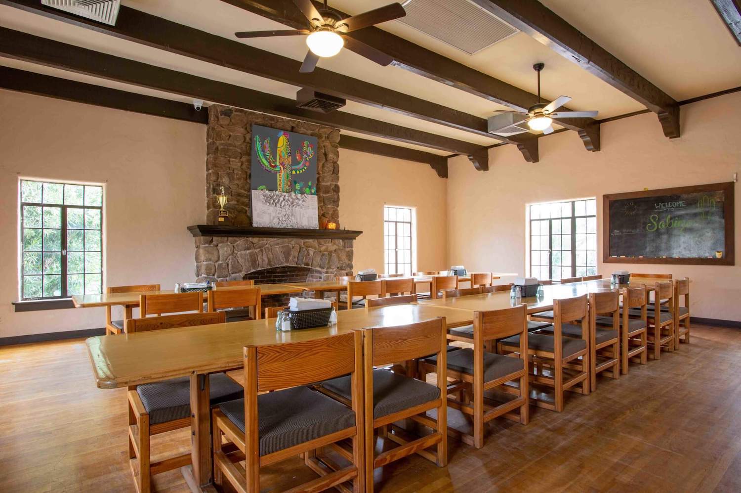 Spacious dining area with wooden tables, stone fireplace, and warm lighting at Sabino Recovery