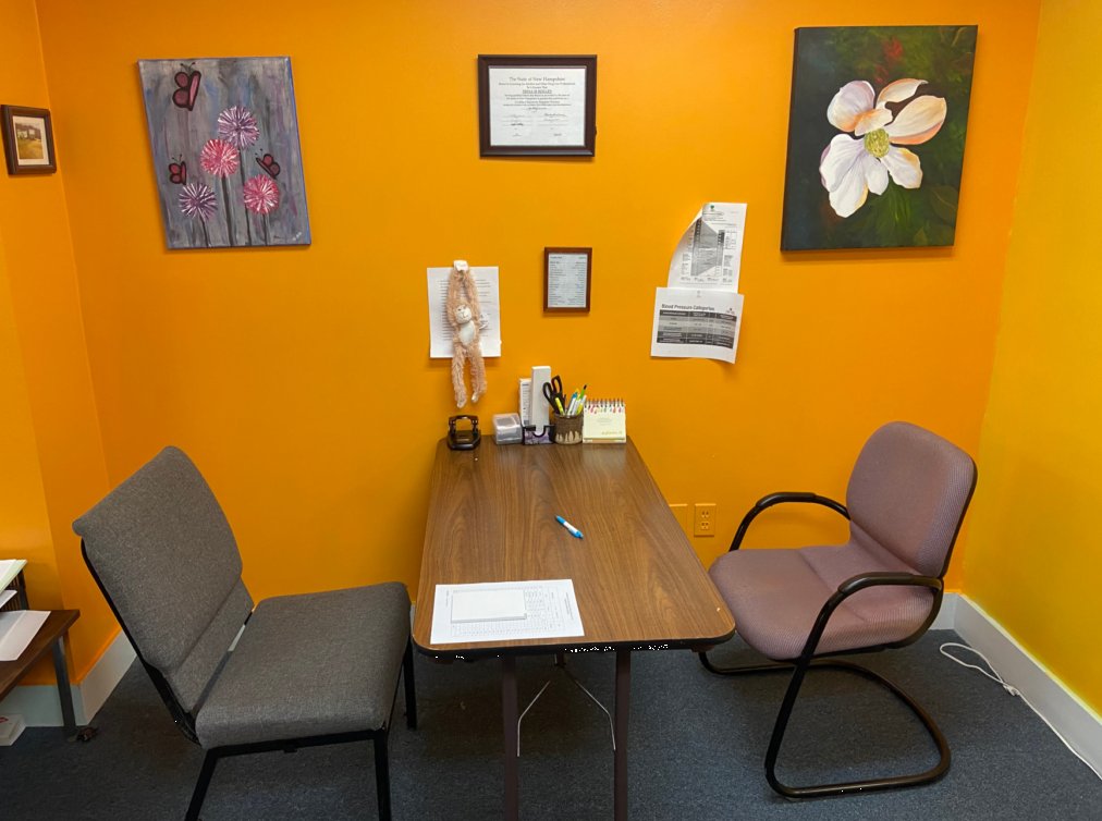 Warm consultation room with two chairs, desk, and wall art
