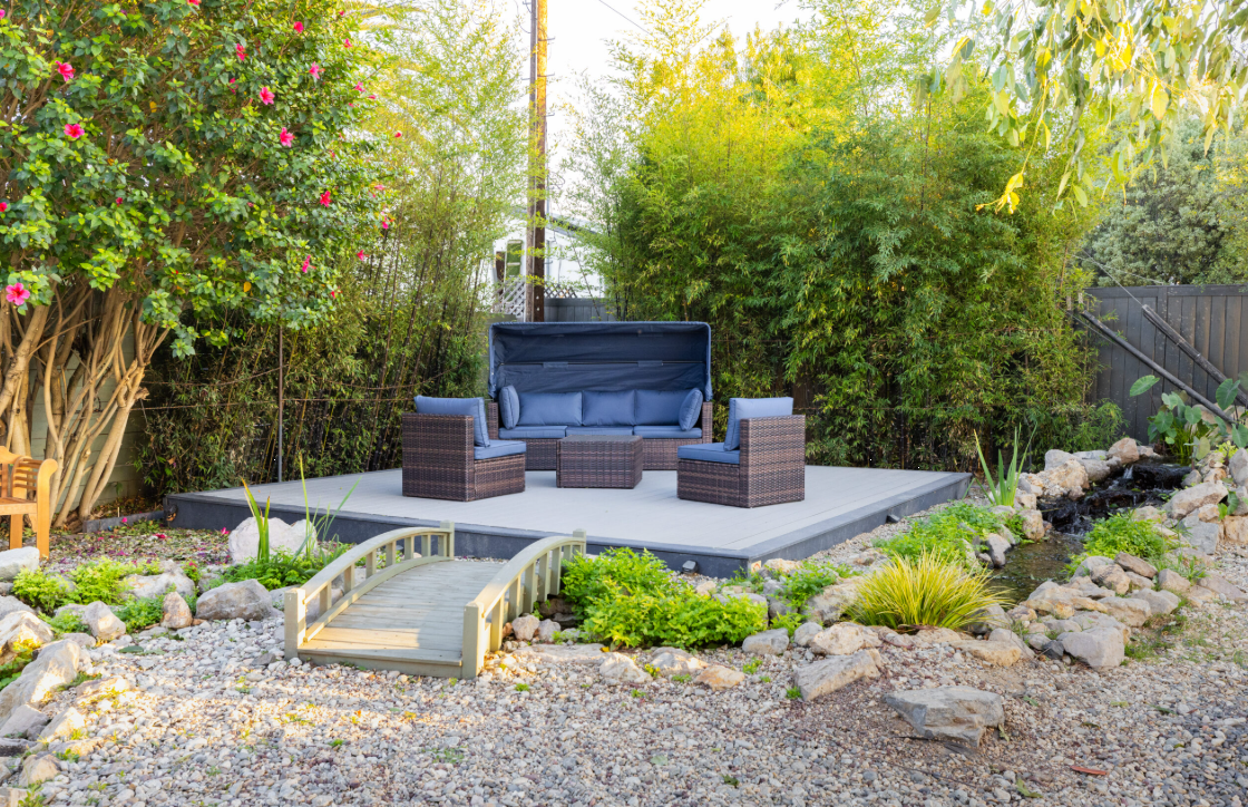 Outdoor deck with wicker chairs near small bridge