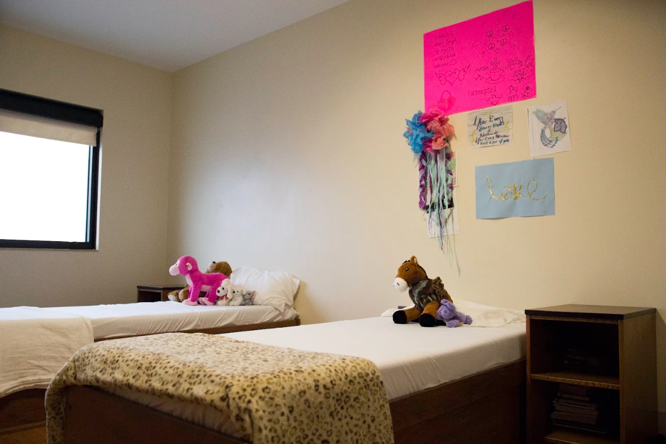Shared bedroom with two beds, stuffed animals, and wall art.