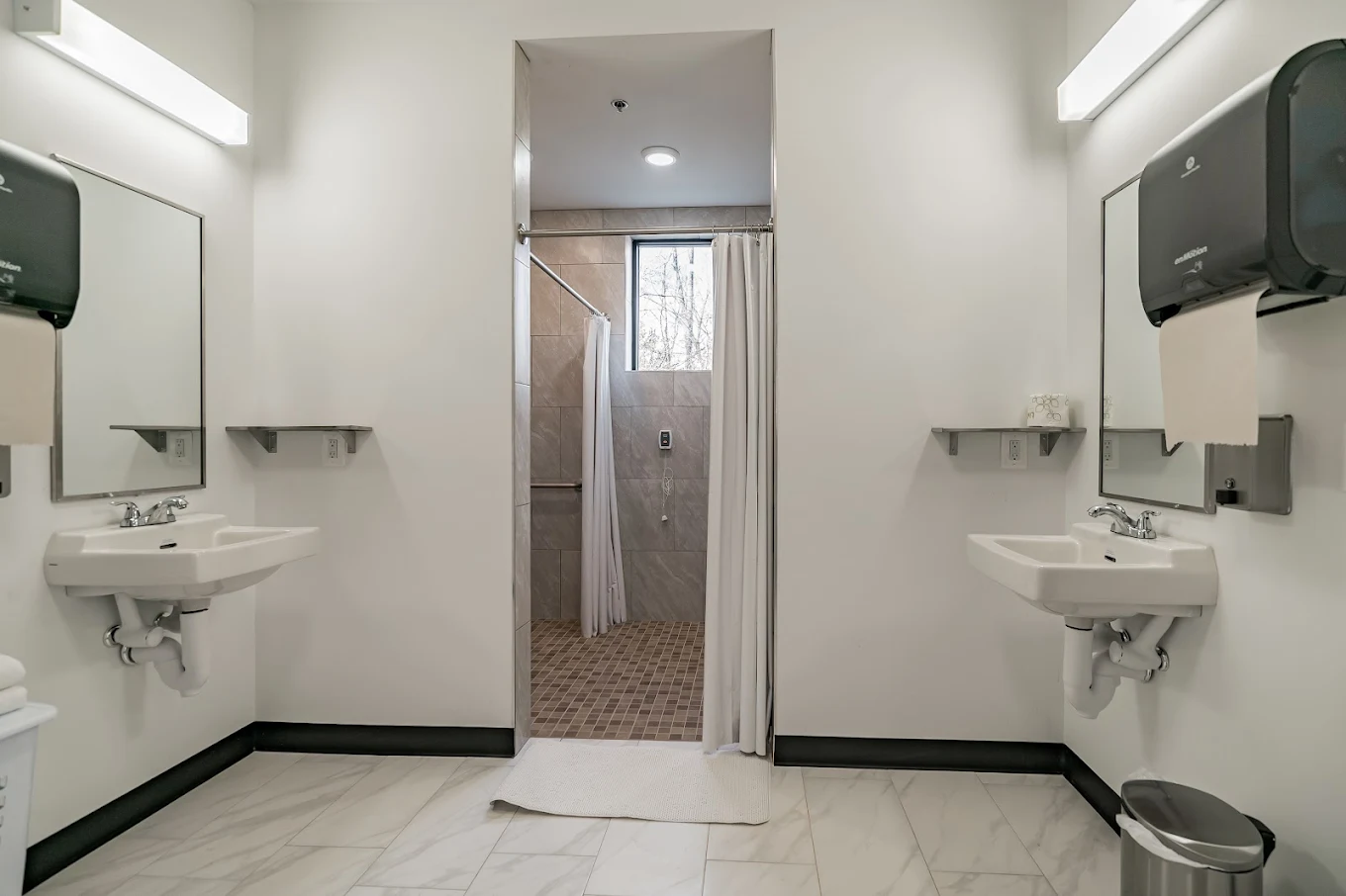 Clean shared bathroom with sinks and walk-in shower