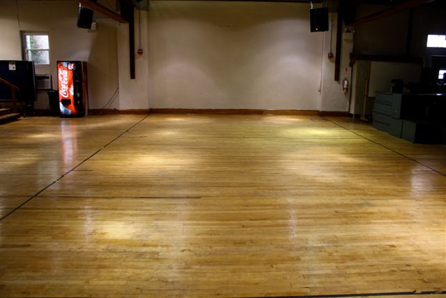 Open recreation hall with wooden floors and vending machine