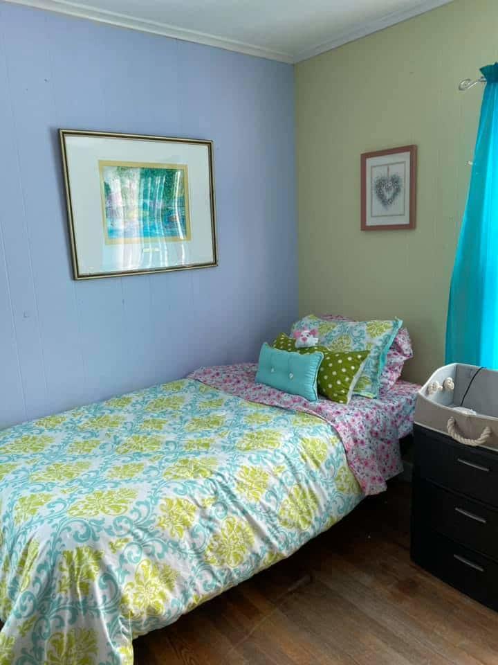 Twin bed with pastel bedding and framed wall art