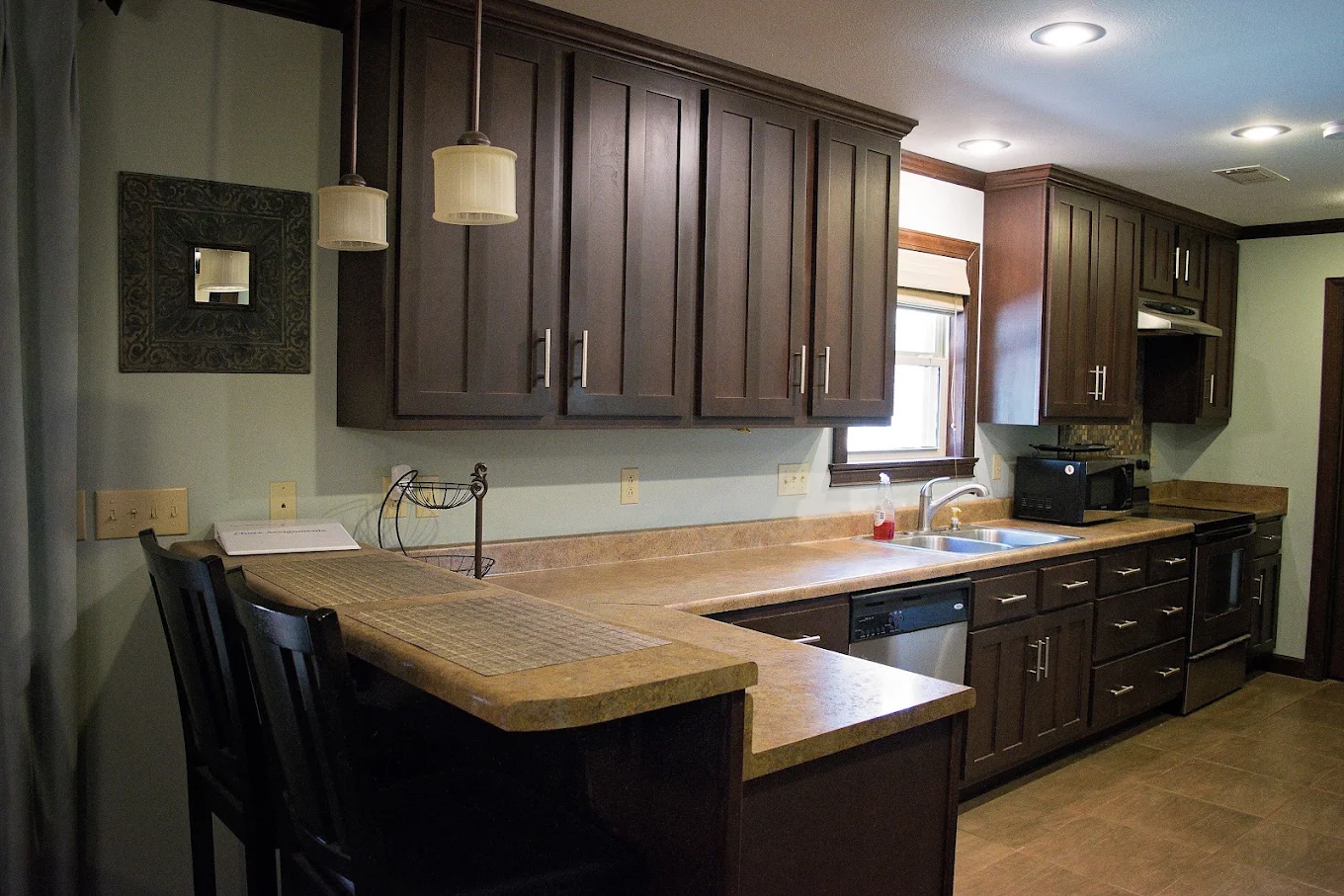 Full kitchen with dark cabinets, appliances, and counter seating
