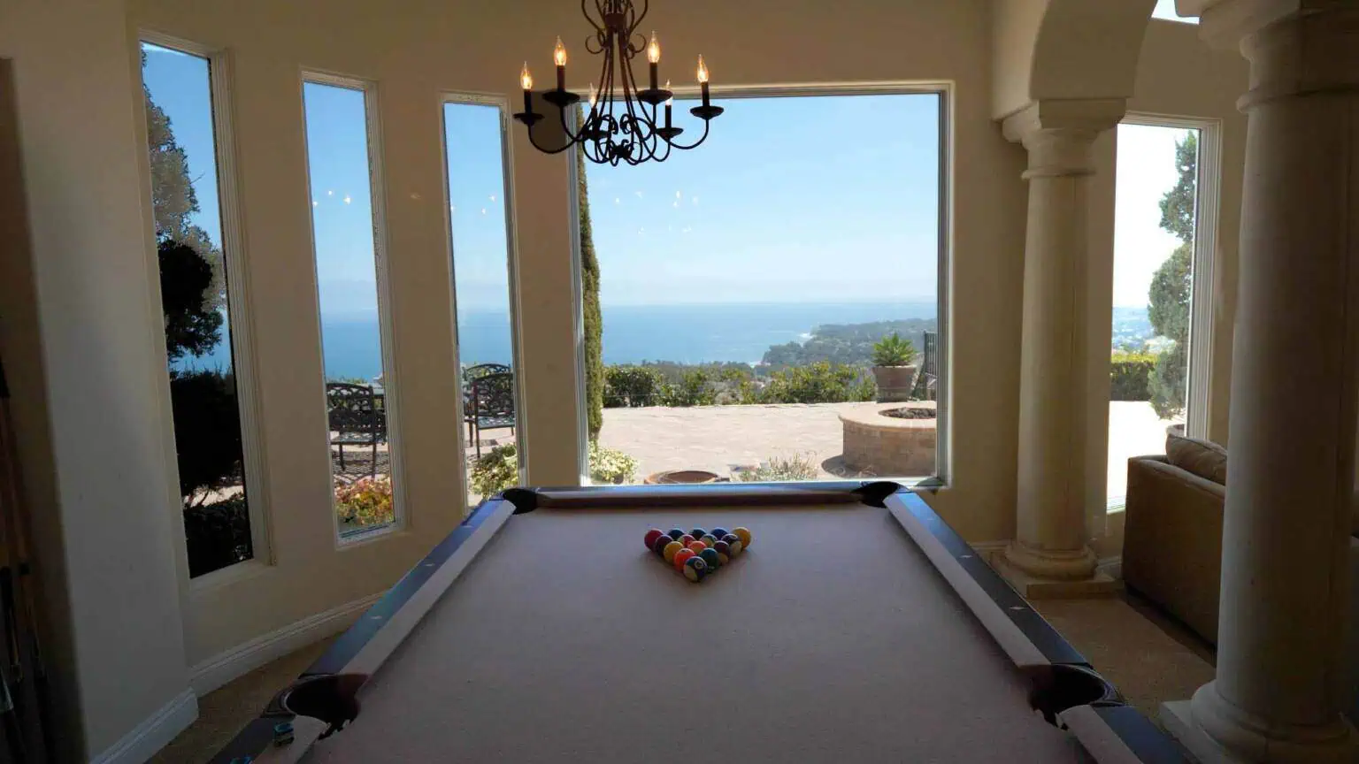 Game room with pool table and large windows overlooking ocean