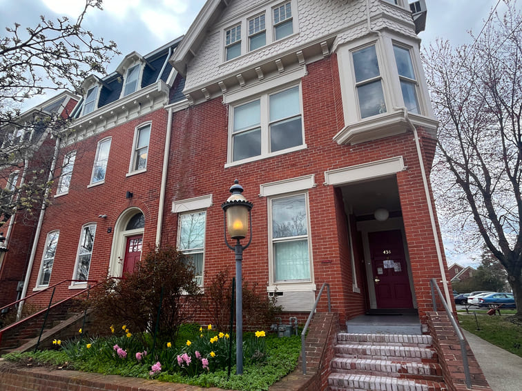 Red brick building with flower beds and steps to the entrance