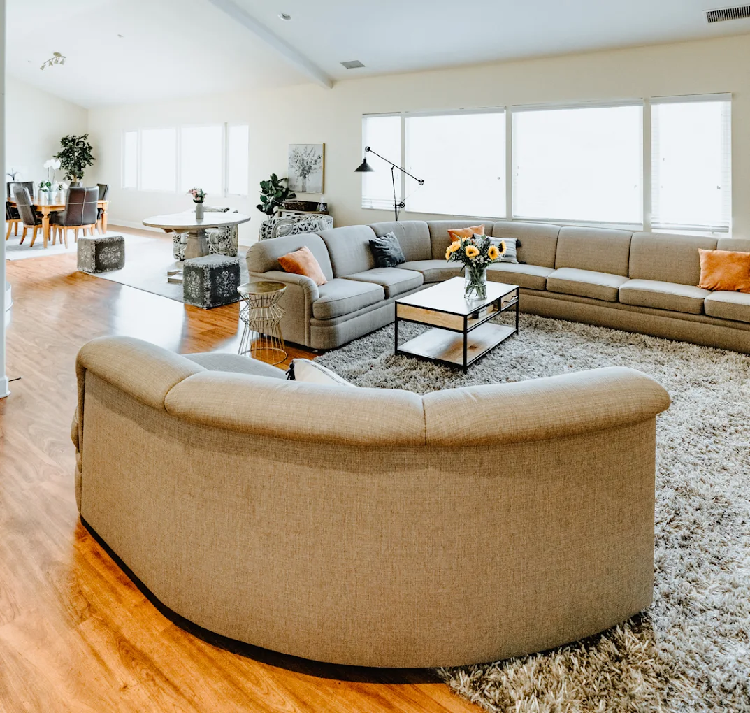 Spacious lounge with gray sectional and sunlit windows