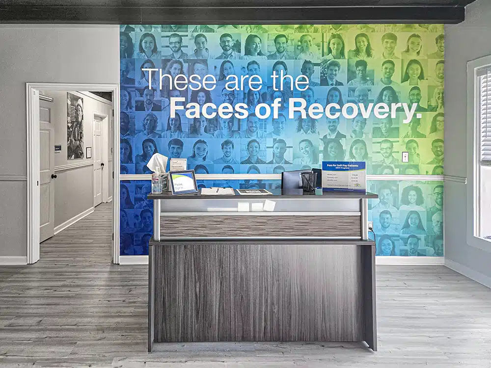 Reception desk with “Faces of Recovery” mural backdrop