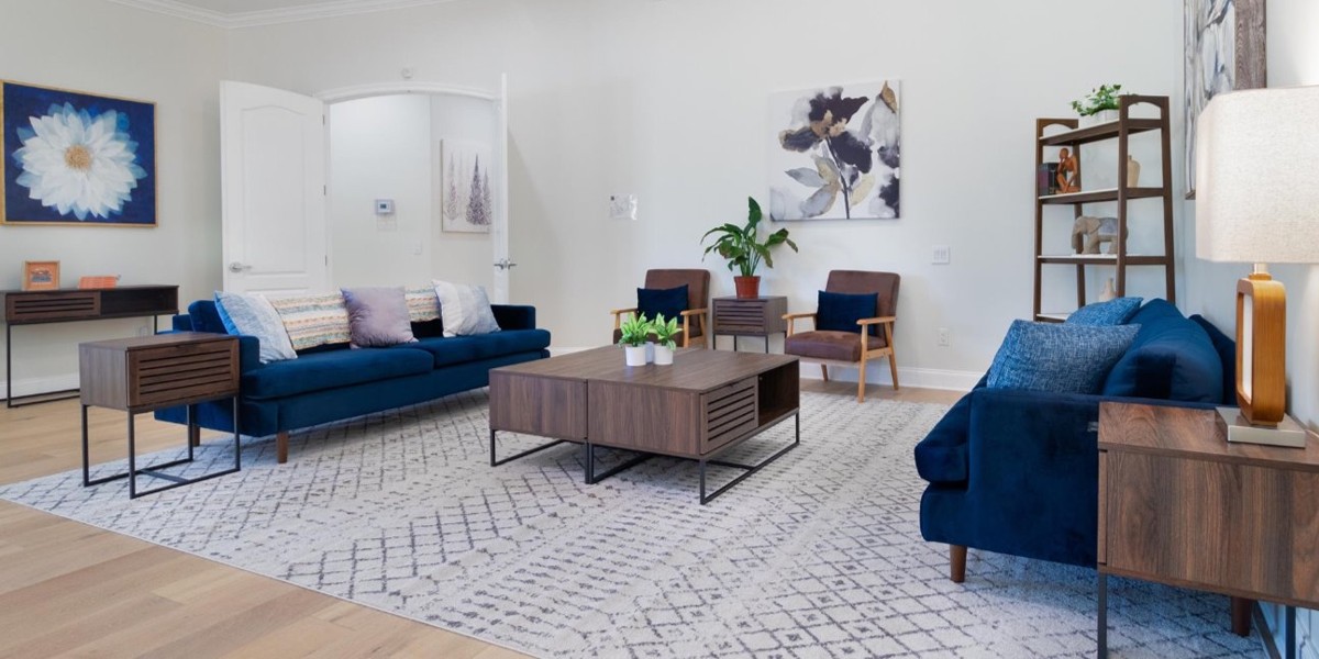 Modern living room with blue sofas, wooden tables, and wall art