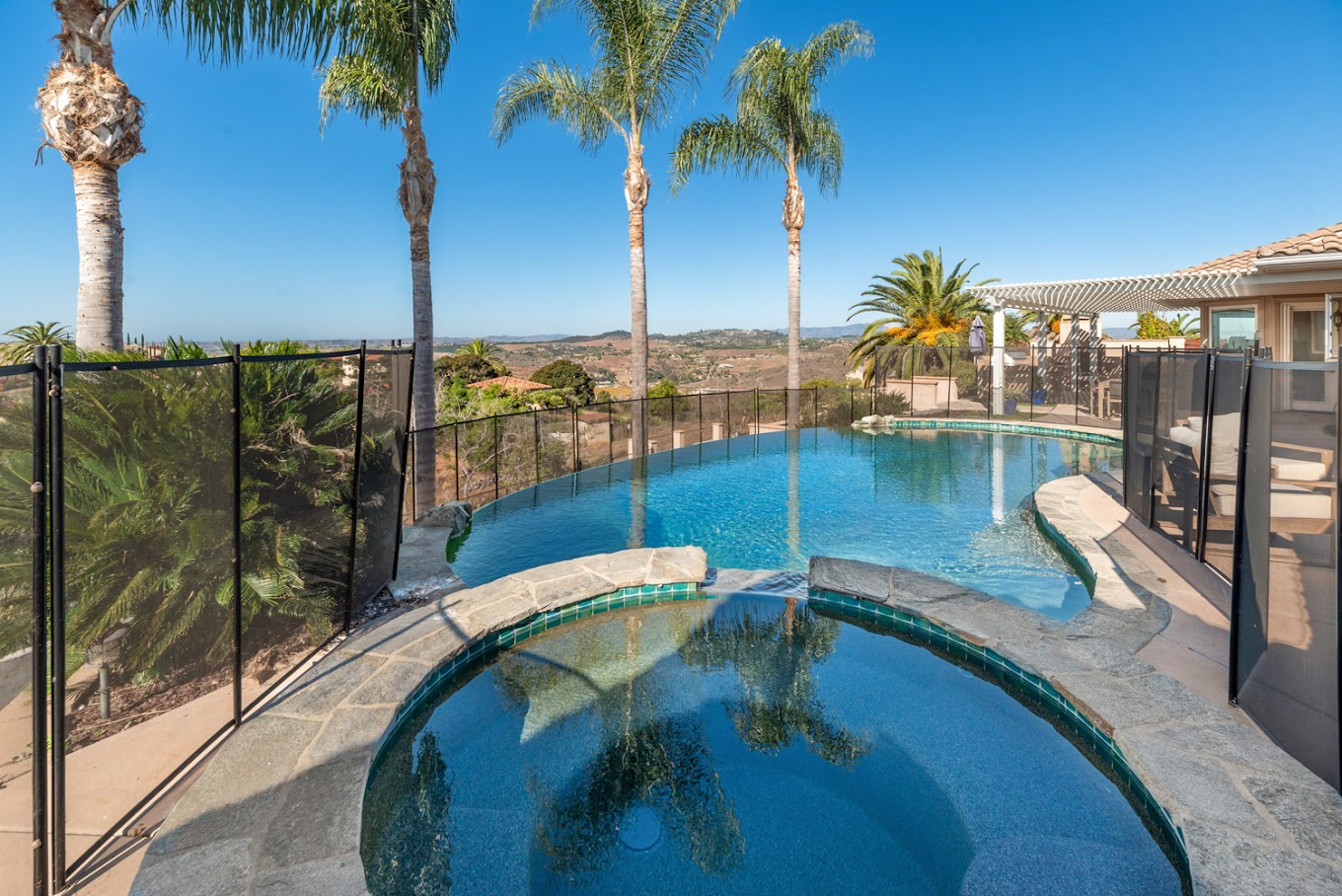 Outdoor recreation space with pools, palm trees and hillside view.