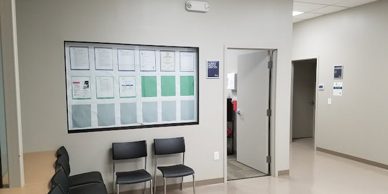 A clean and organized waiting area with neatly arranged chairs, a window displaying important information, and a hallway leading to private offices.