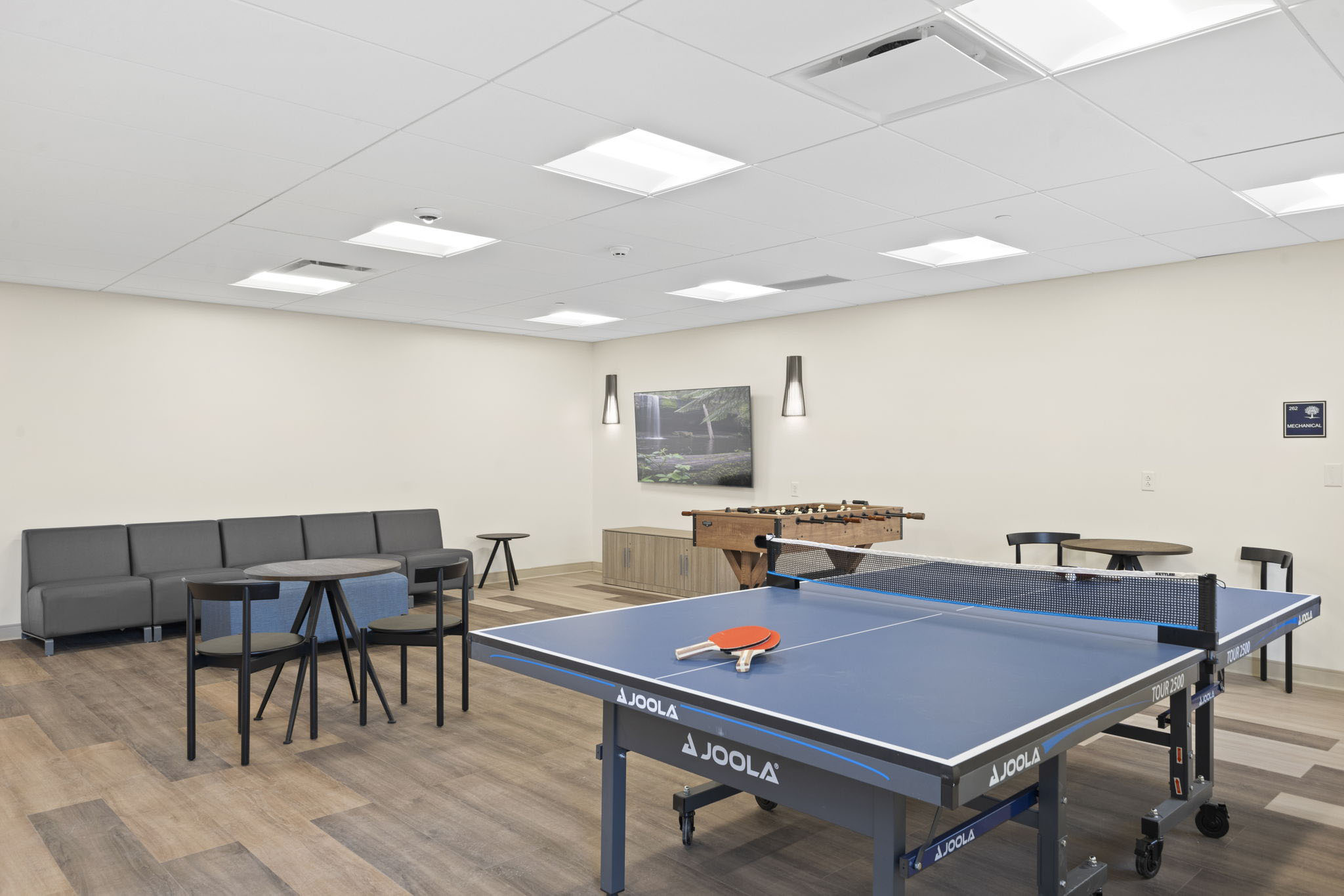 A recreation room with a ping pong table and seating.