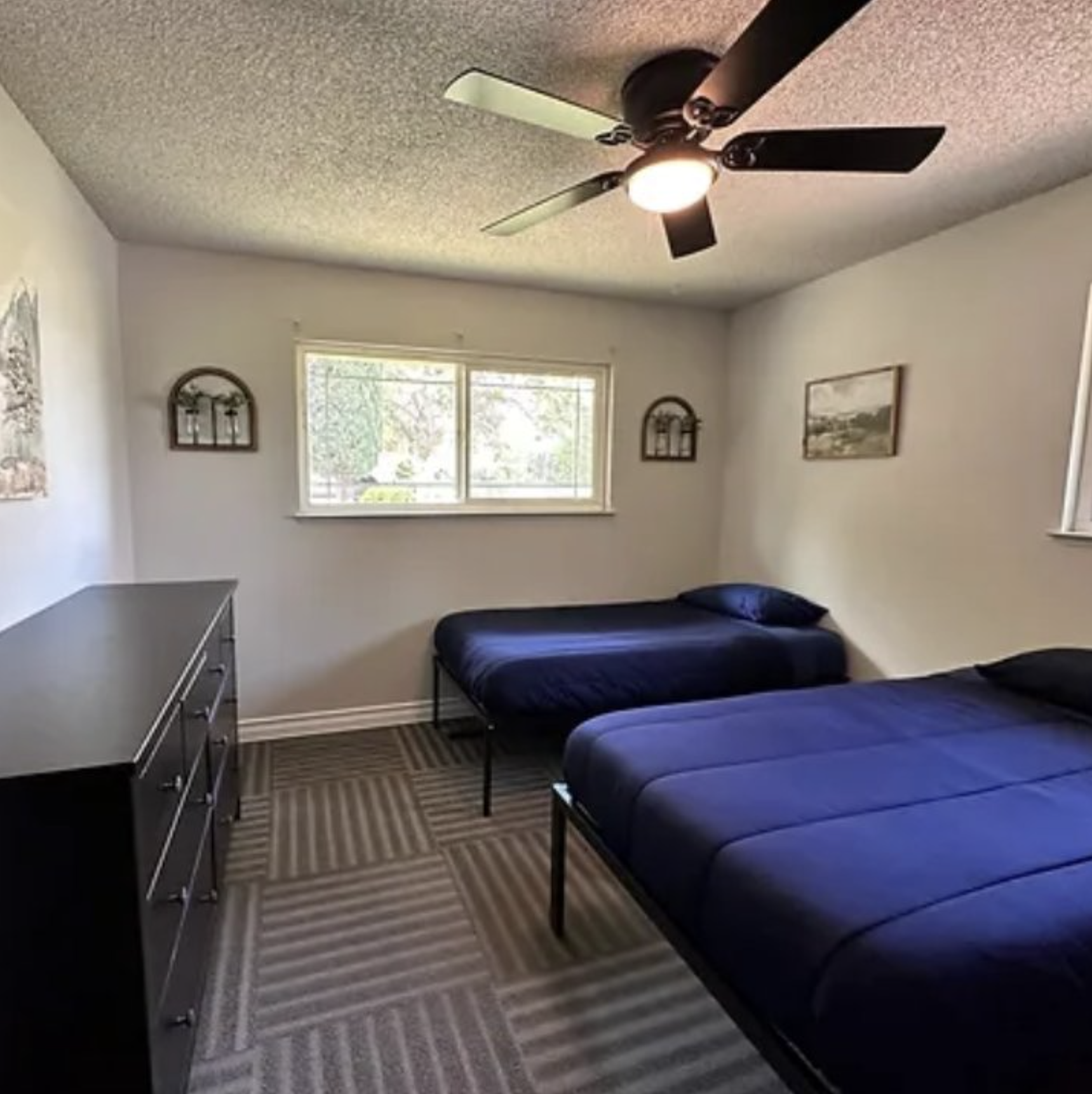 Shared bedroom with two beds, bright walls, and minimal furnishings.