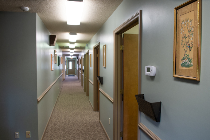 Long hallway with doors to private rooms and handrails