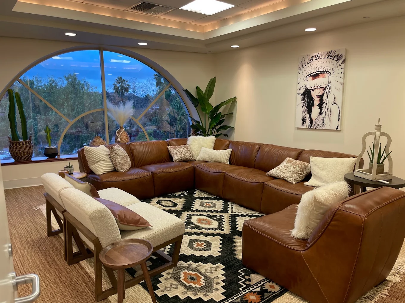 Large leather sectional facing arched window with plants