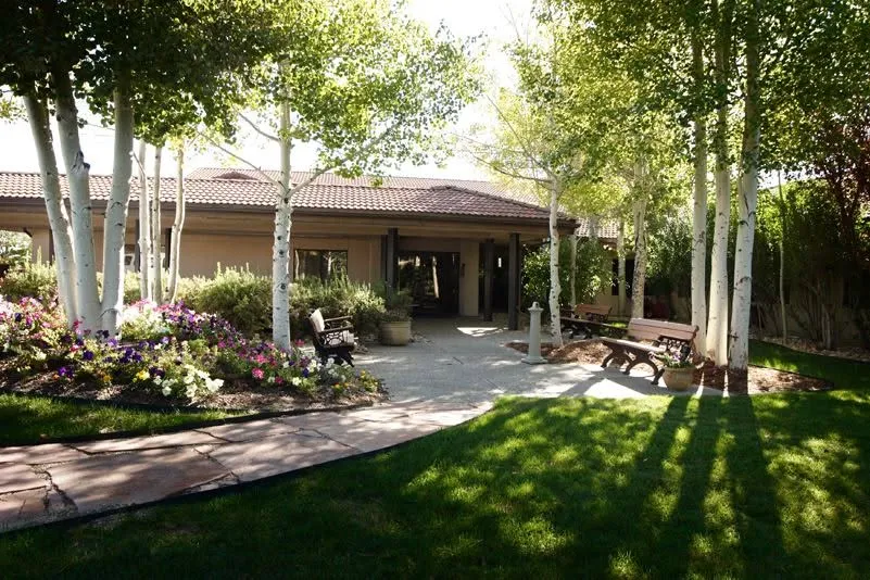 Landscaped courtyard and facility exterior at Wyoming Behavioral Institute in Casper, with trees, flowers, and benches