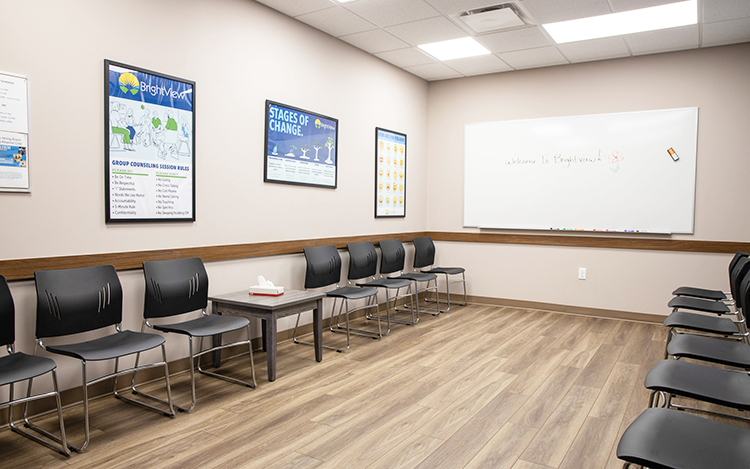 Group therapy room with chairs, whiteboard, and recovery posters