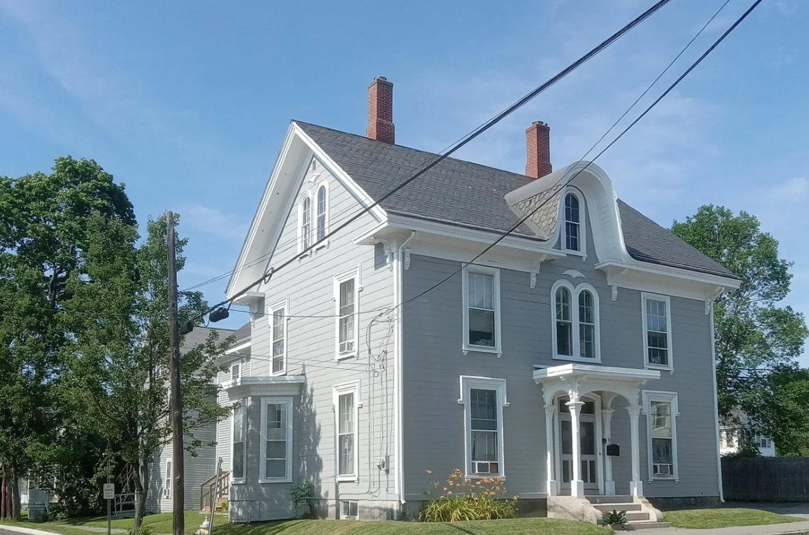 Large gray Victorian house with white trim and two brick chimneys