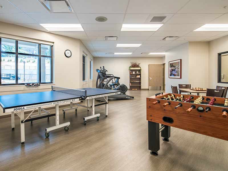 Recreation room with ping pong table, foosball table, and exercise equipment inside treatment facility
