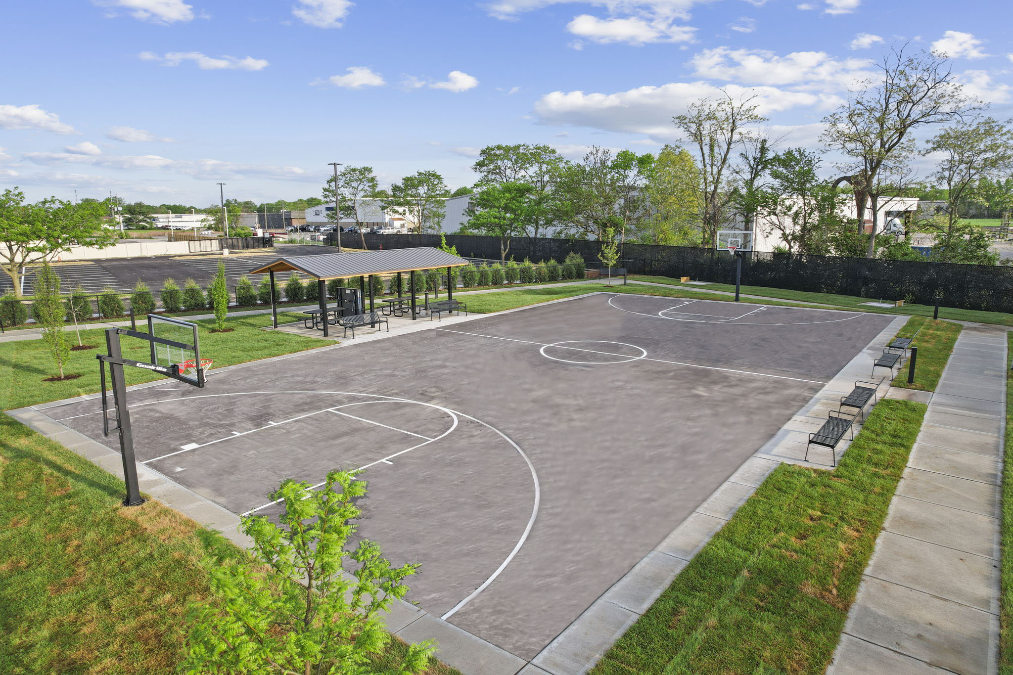 An outdoor basketball court with a covered seating area.