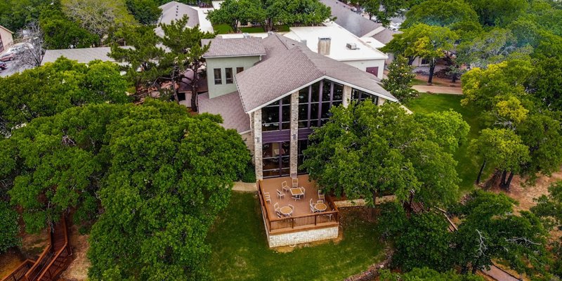  Aerial view of a beautiful building nestled among lush green trees, featuring a spacious outdoor deck perfect for relaxation and gatherings.