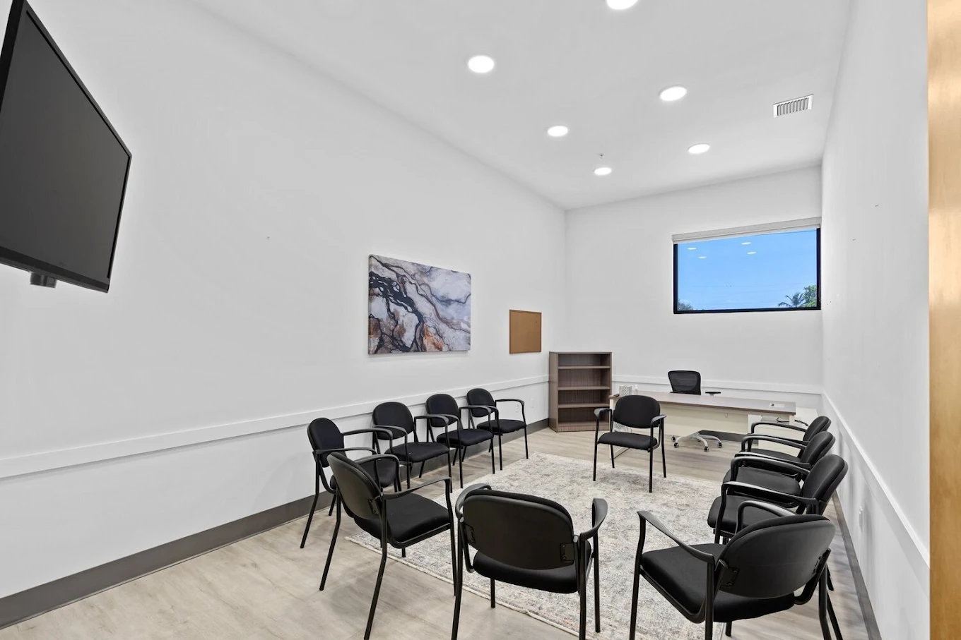 Room with chairs, desk, window, and wall-mounted TV