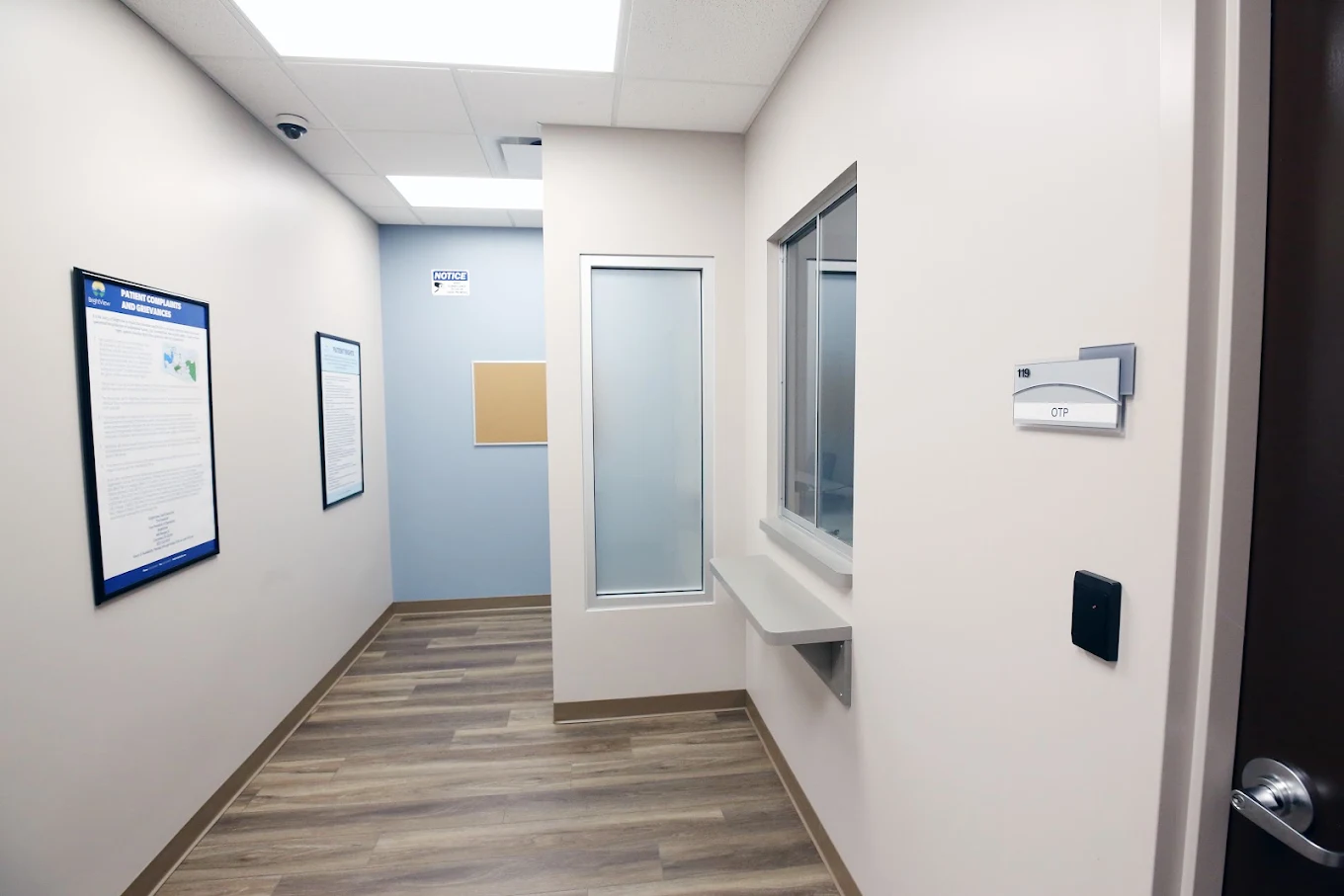 BrightView Elyria clinical hallway with service window, patient information posters, and treatment room entrance