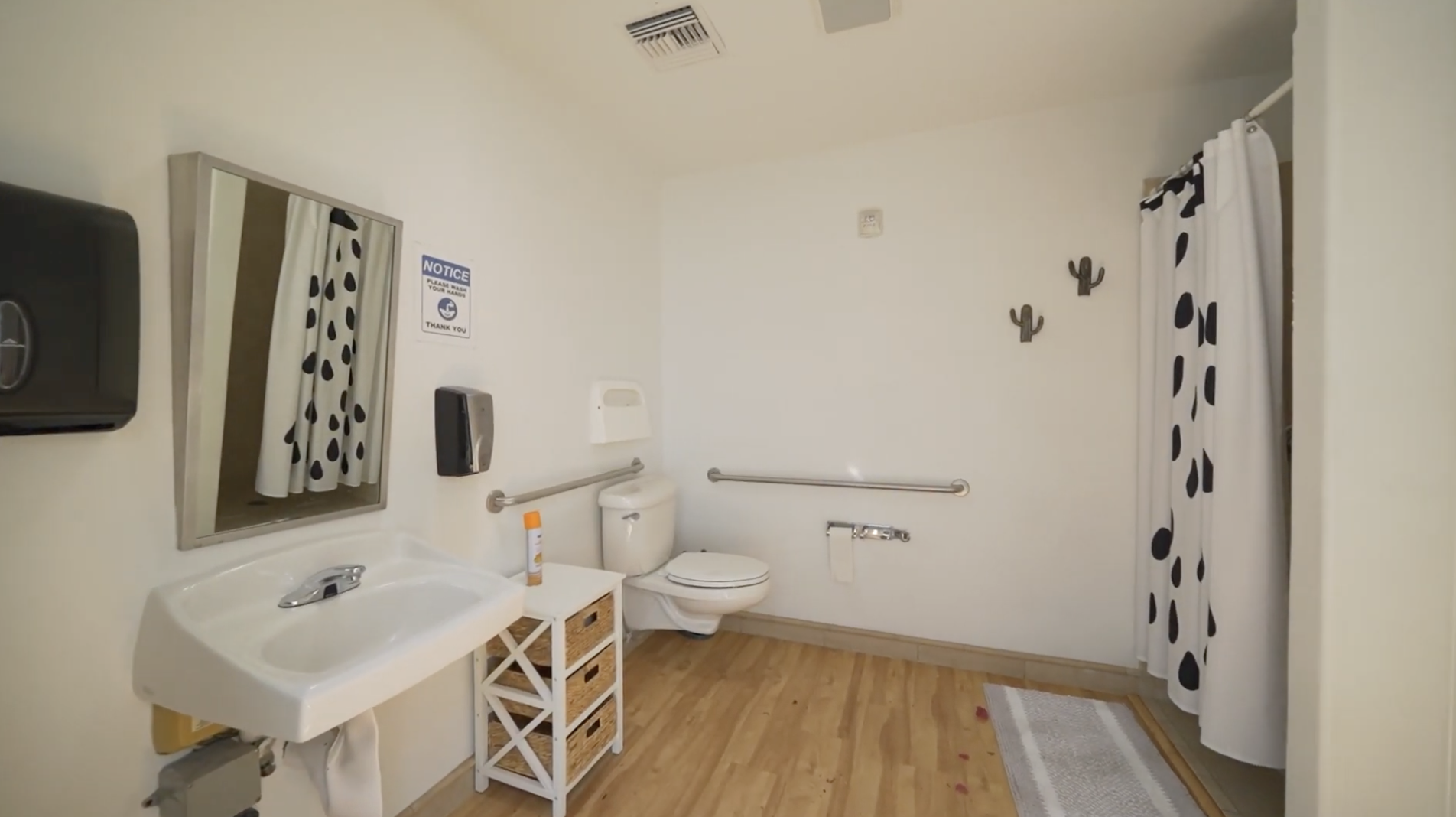Spacious bathroom with grab bars, sink, and shower area