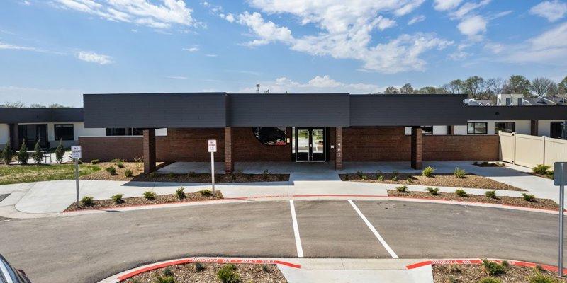  A modern, single-story building with a sleek design, large entrance, and well-maintained landscaping. The clear skies enhance the welcoming atmosphere.