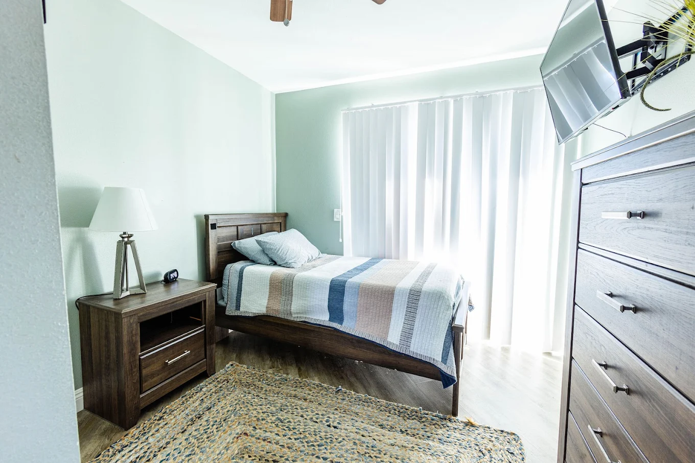 Private bedroom with natural light and mounted TV