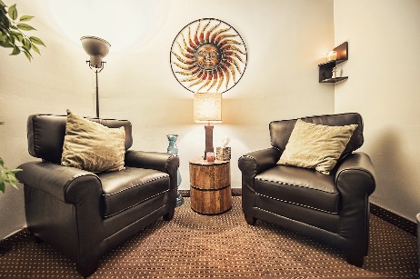 Two armchairs with side table in softly lit therapy room