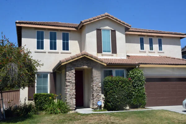 Two-story tan house with brown trim and front lawn