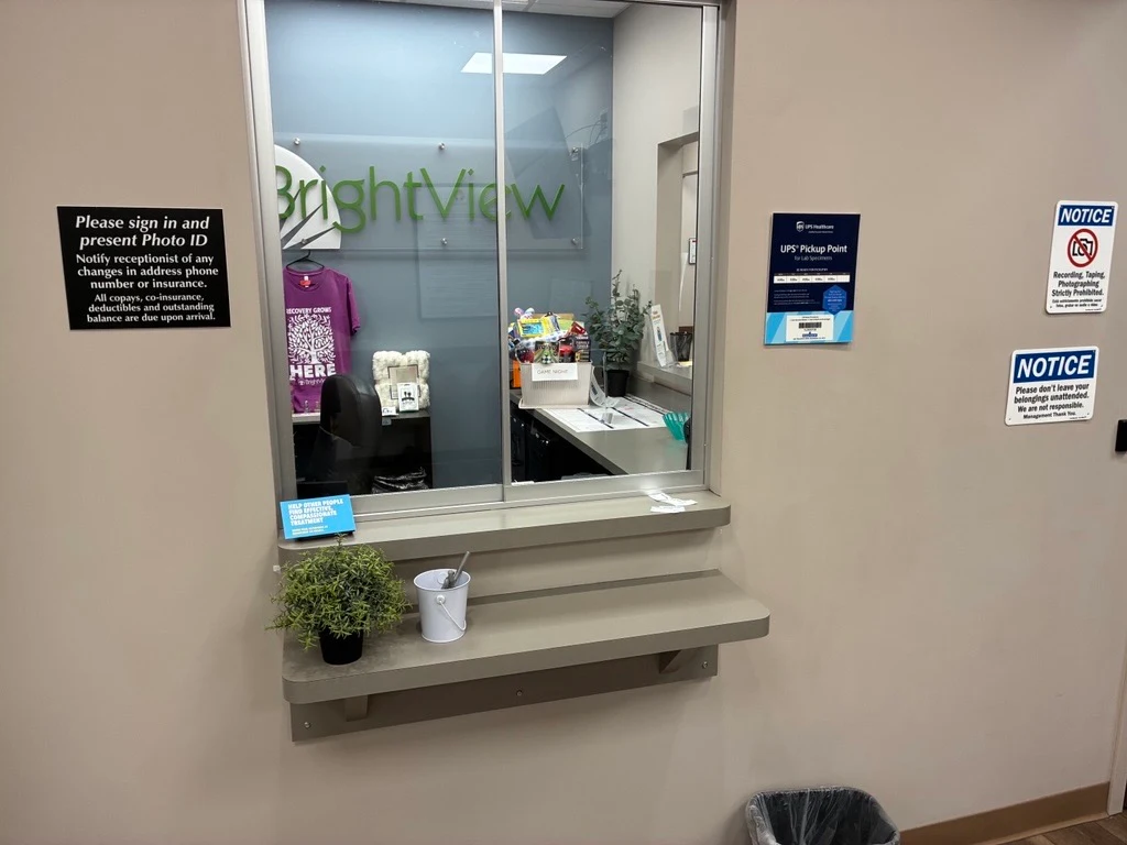BrightView Health Youngstown reception window with counter, informational notices, small plant, and office visible behind glass
