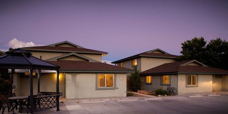 Modern residential buildings at dusk with a peaceful outdoor seating area under a gazebo, surrounded by a serene and welcoming environment.