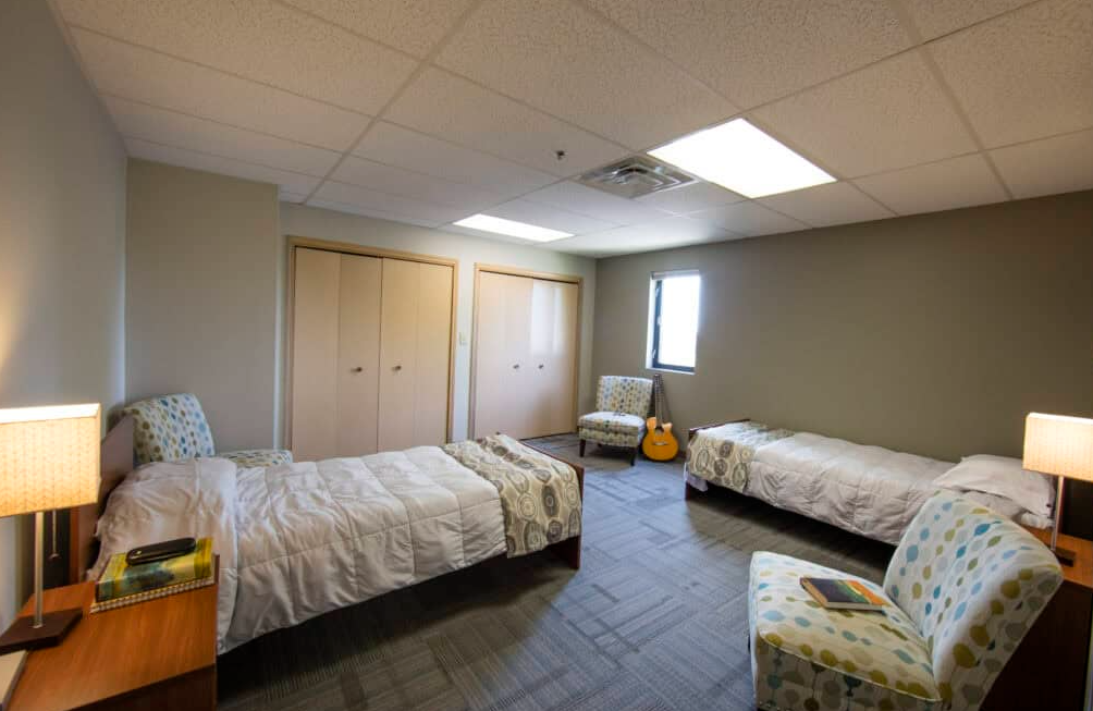 Shared patient bedroom with two beds and seating area