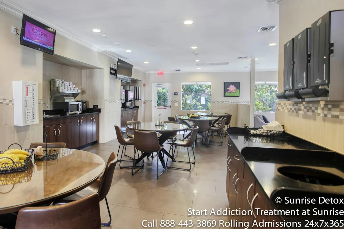 Cafeteria with round tables, kitchen counter, and mounted TVs