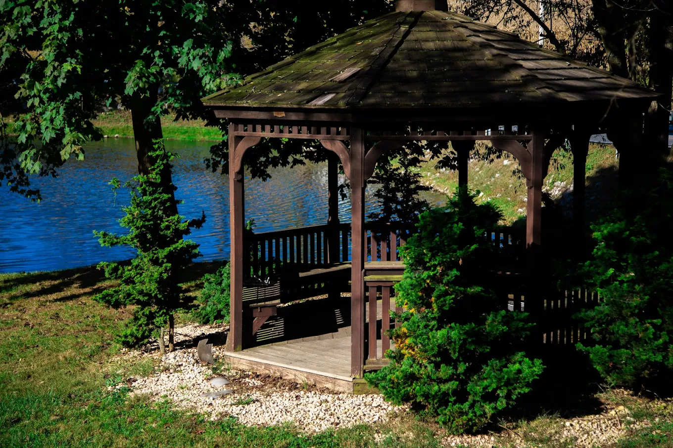 Wooden gazebo by lake surrounded by trees