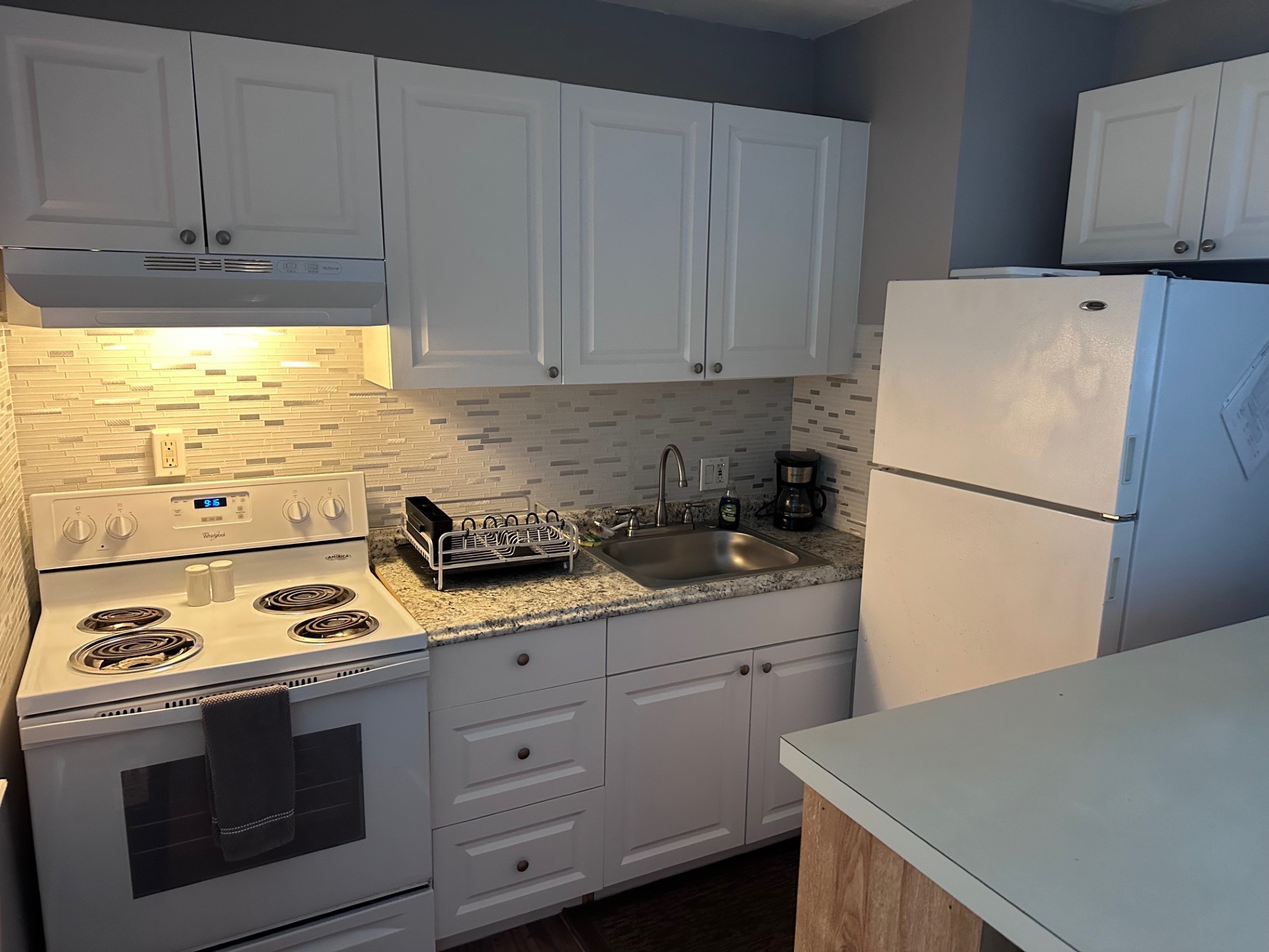 Compact kitchen with white cabinets and appliances