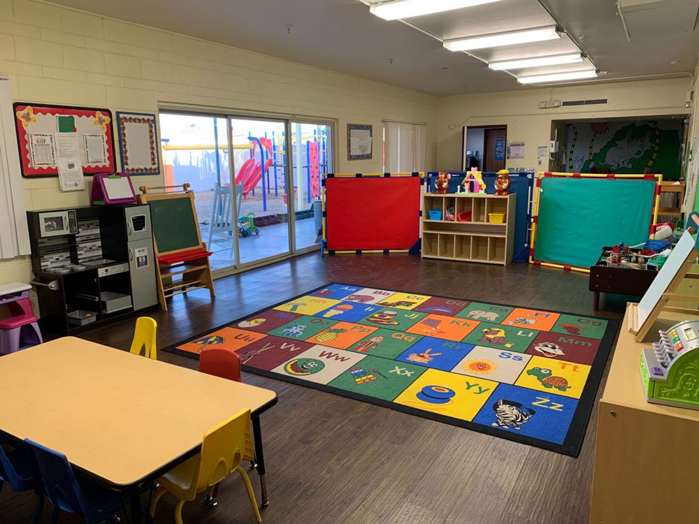 Classroom with colorful alphabet rug, toys, and tables