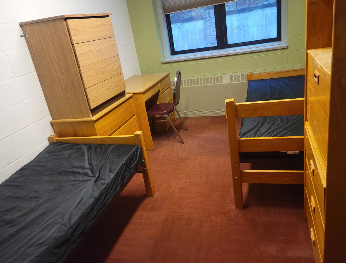 Shared inpatient bedroom with twin beds, desks, and storage
